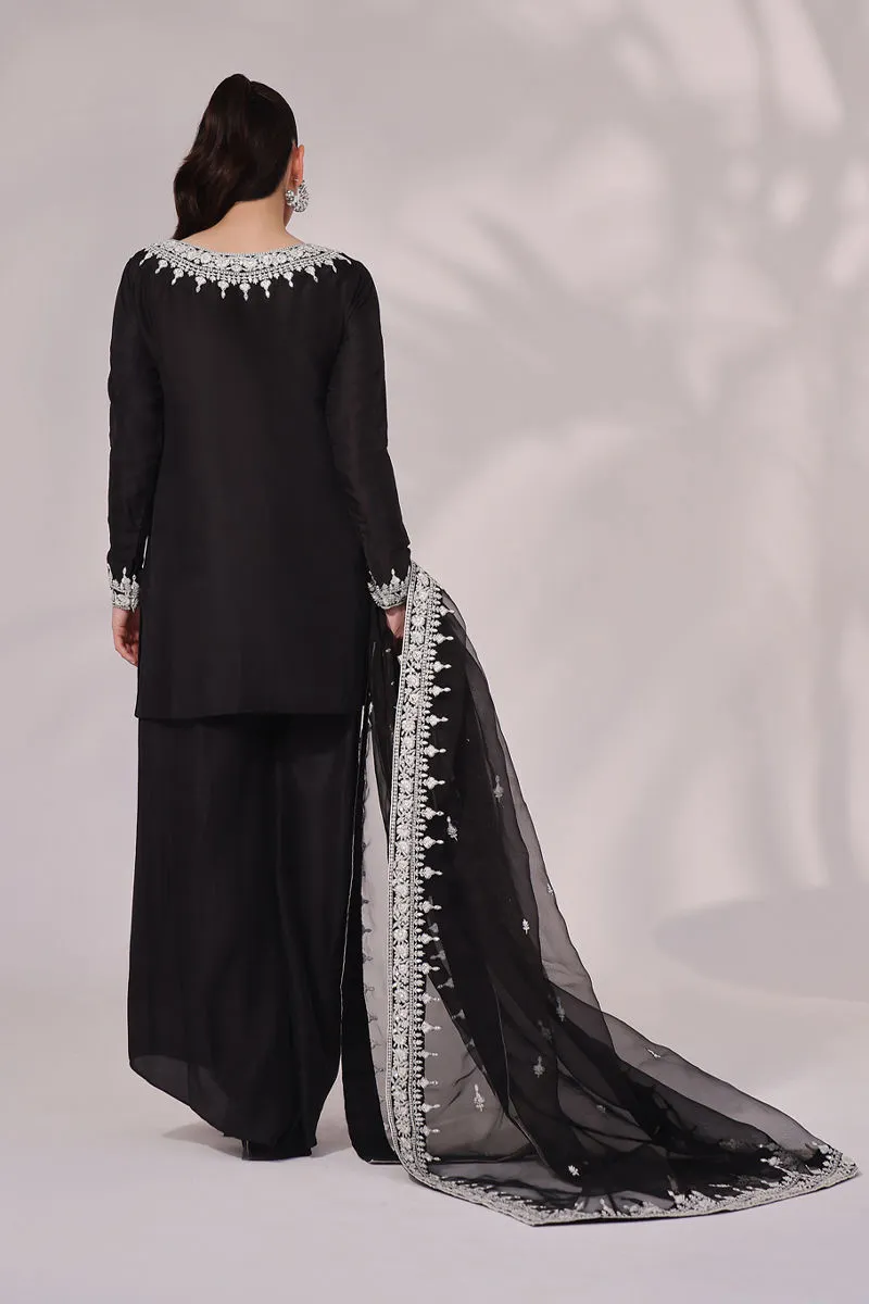 Back view of the Inaya Black & White Raw Silk Set, highlighting the luxurious fabric and elegant dupatta. The intricate embroidery and mirror work are a stunning feature.