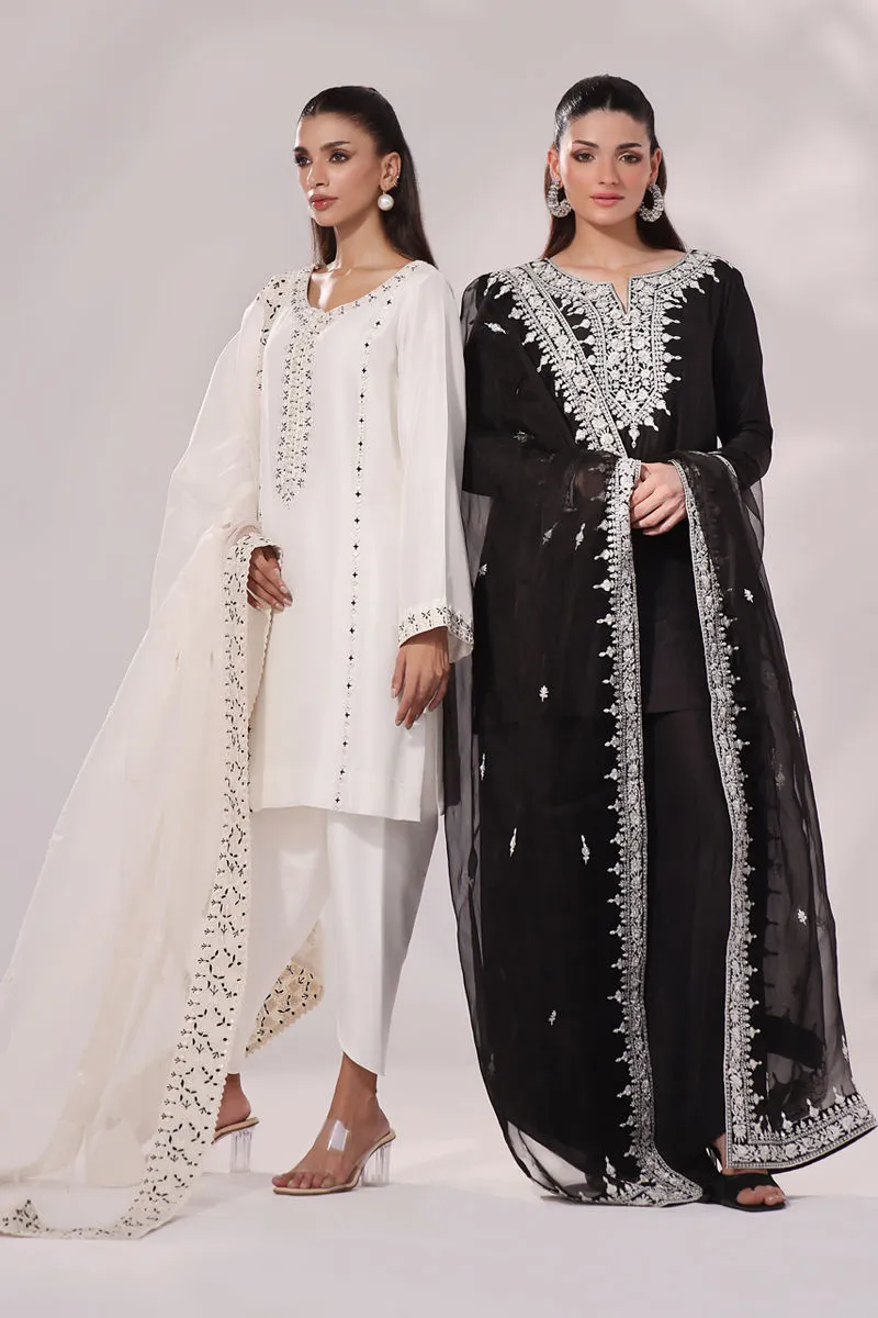 Modern model in white dress stands alongside a model in the Inaya black and white raw silk set, both showcasing elegant designs for weddings and formal events.