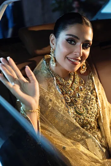 GOLD MASURI NET KALIDAR DRESS displayed with a golden clutch and jewelry.