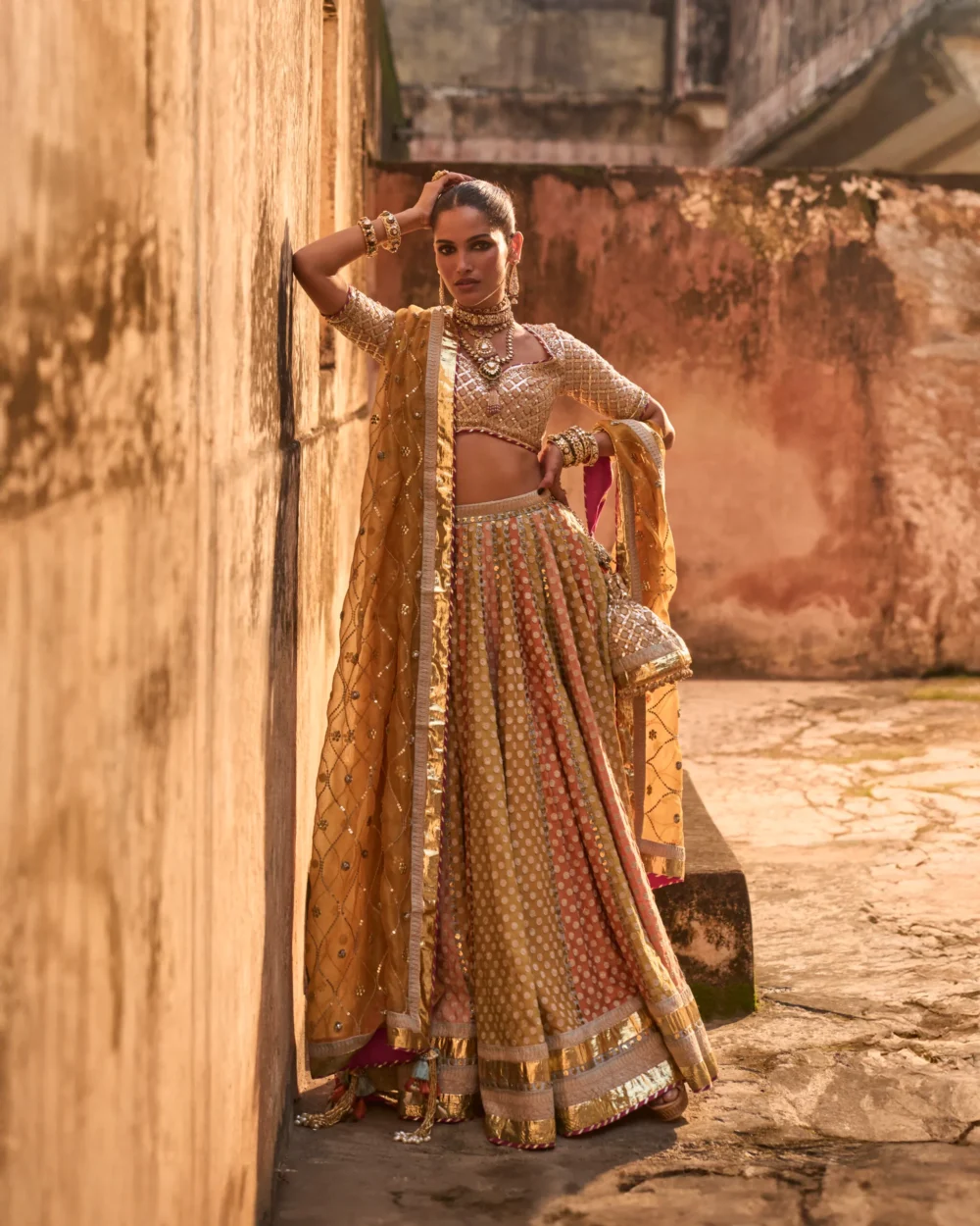 Khaddi Silk Lehenga Set featuring an orange blouse with gota work, a mustard lehenga with ari work panels, and a mustard organza dupatta. Khaddi Silk Lehenga Set featuring an orange blouse with gota work, a mustard lehenga with ari work panels, and a mustard organza dupatta.