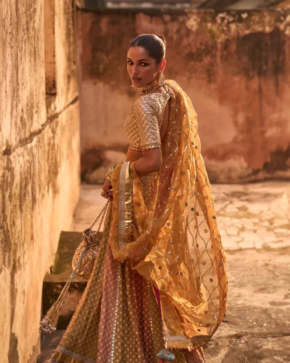 Khaddi Silk Lehenga Set featuring an orange blouse with gota work, a mustard lehenga with ari work panels, and a mustard organza dupatta. Khaddi Silk Lehenga Set featuring an orange blouse with gota work, a mustard lehenga with ari work panels, and a mustard organza dupatta.