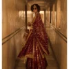 A woman gracefully poses in a stunning Maroon Jamavar Lehenga Set, exuding elegance and sophistication.