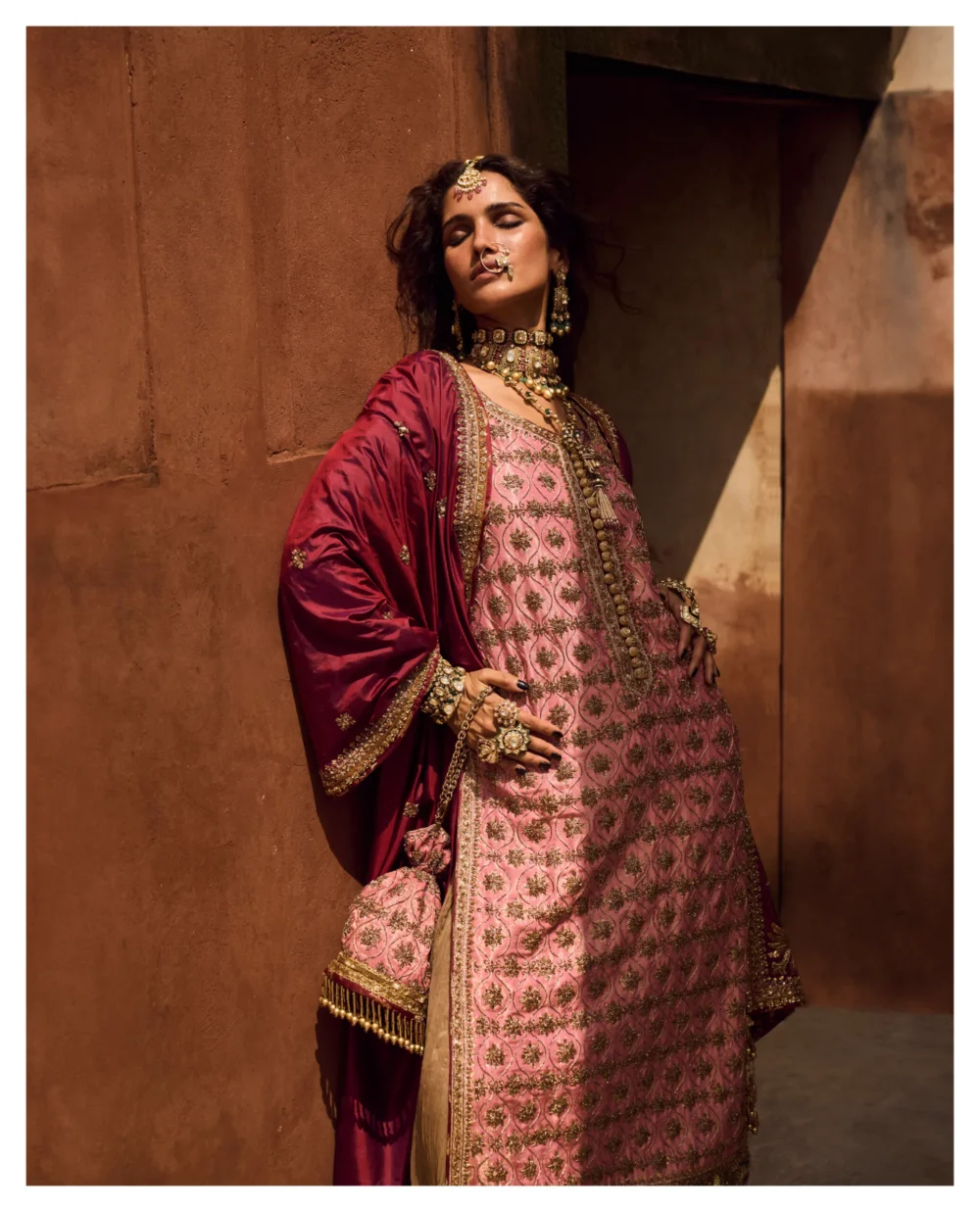A woman gracefully poses in a stunning Candy Pink Mysori Net Lehenga Set, exuding elegance and sophistication.