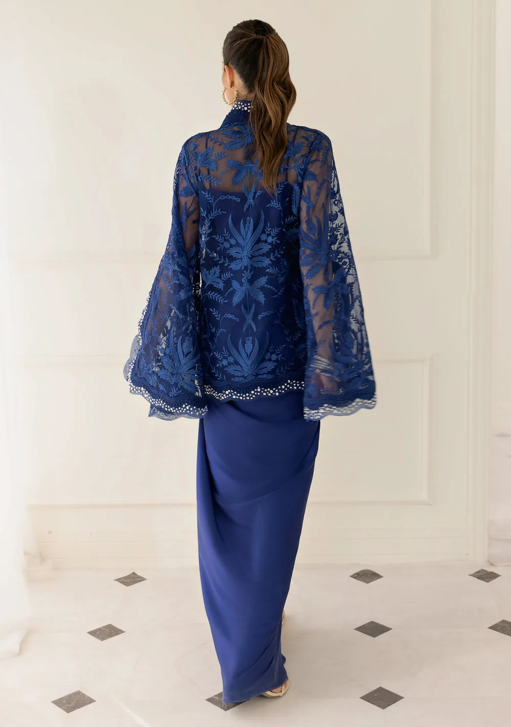 download (11) Model in royal blue organza cape and asymmetrical silk sarong skirt for a modern Eid 2026 glam look.