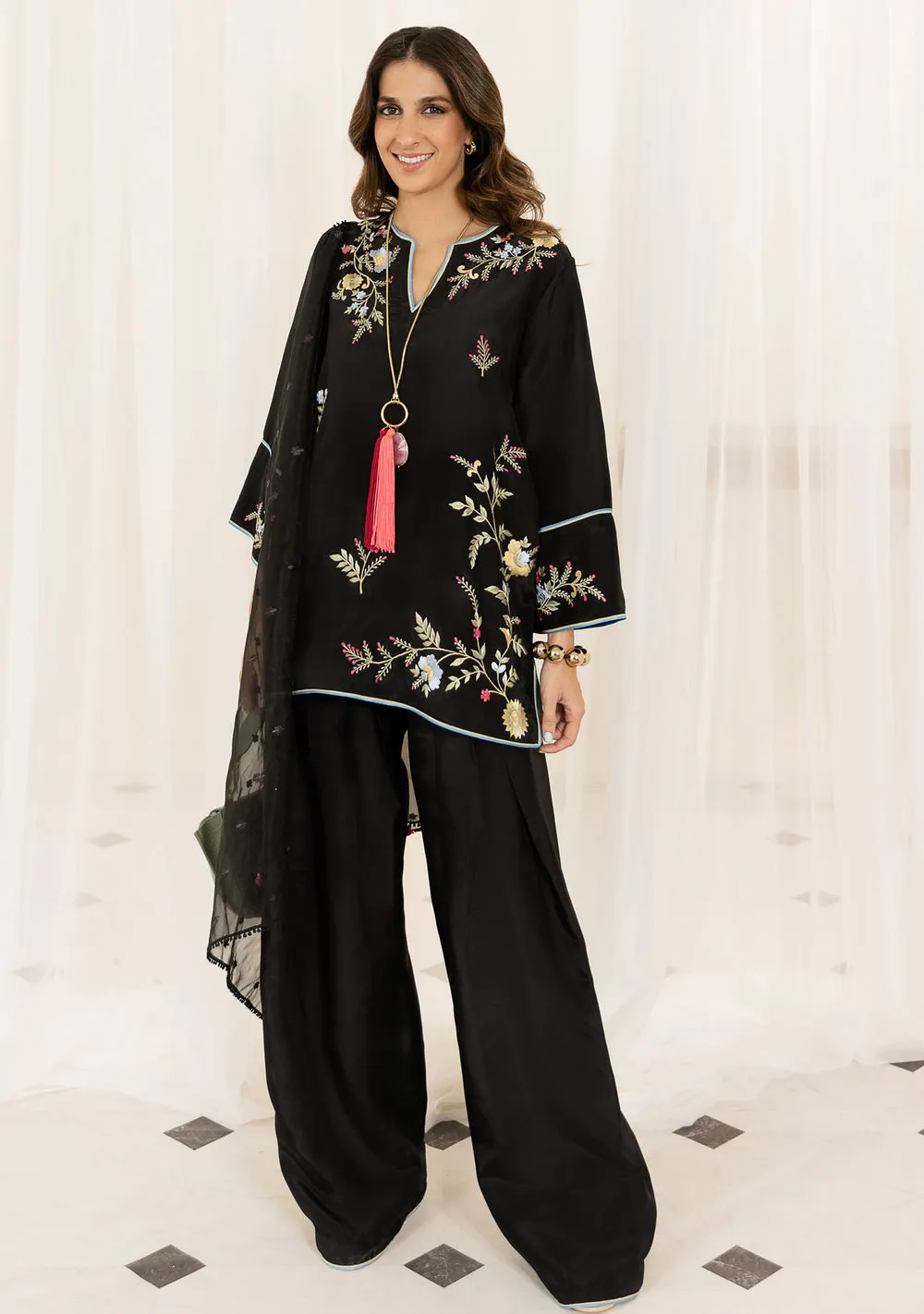Model in black oversized short kurta with wide-leg kharri shalwar and organza dupatta for Eid 2026 fashion.