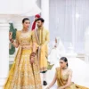 mustard-golden-lehenga-bridal-campaign-full-silhouette-gota-zardozi-hand-embroidered-hammad-bespoke-official.webp golden lehenga bridal standing seated duo Gota Resham embroidery barat Hammad Bespoke Official