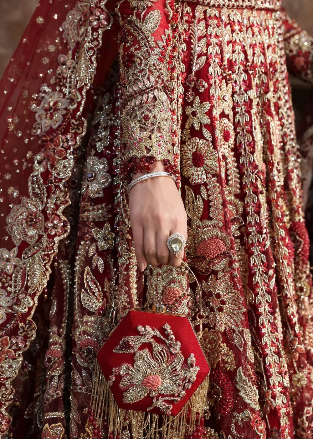 Detail shot gold Zardozi sleeve embroidery and tasselled bridal clutch — red net lehenga for wedding, Hammad Bespoke Official