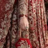 Detail shot gold Zardozi sleeve embroidery and tasselled bridal clutch — red net lehenga for wedding, Hammad Bespoke Official