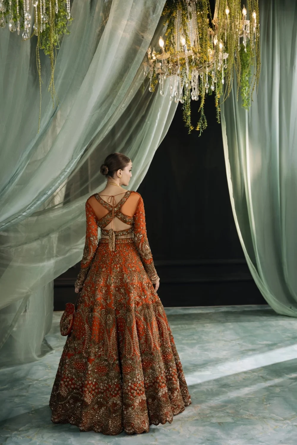 Back view orange organza bridal lehenga showing cross-back choli and 240-inch flared skirt — Hammad Bespoke Official